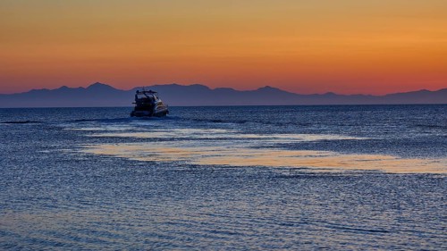 Lonely boat on the sea with mountains in the background, sunrise, dawn, Fort of Saint Nikolaos,