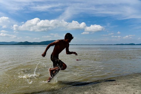 Boys jump in the Brahmaputra river during an a hot summer day in Guwahati, india on July 11, 2022