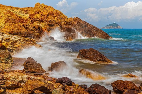 Rugged rocks and foaming spray on Topinetti beach, near Rio Marina, Elba Island, Tuscan Archipelago