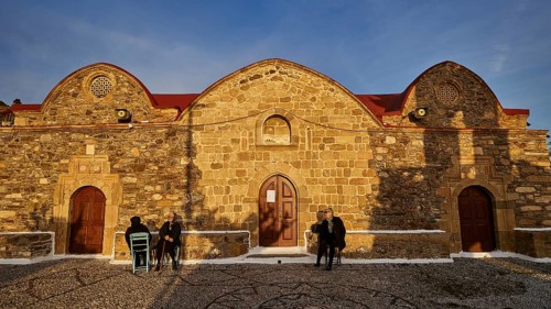 Historic stone church under the evening sun with people sitting in front of it, Easter 2025, Church