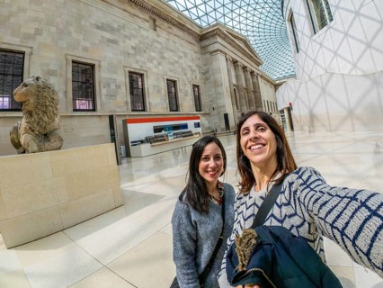 Two happy female tourists are taking a selfie with a fisheye lens at the british museum's great