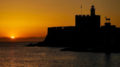 Majestic silhouette of a fortress against a glowing sunrise, dawn, Fort of Saint Nikolaos, Mandraki