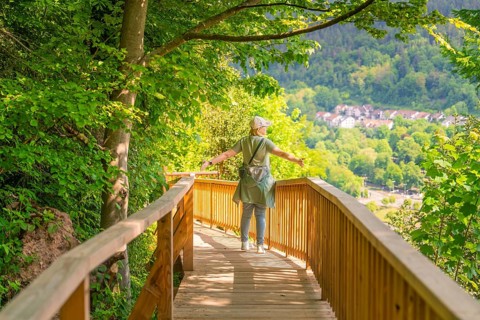 A person walks with outstretched arms on a path and enjoys the view, Panorama Holzsteg, Calw, Black