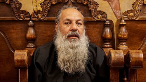 Portrait of a bearded man in black clothes, sitting on a wooden chair, Papas Nektarios, Monastery