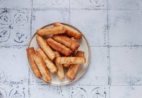 Fried spring rolls with cheese, on a plate, with cream sauce, no people
