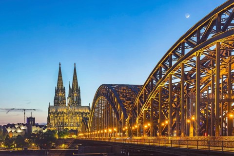 Cologne Cathedral, illuminated in the evening. Hohenzollern Bridge, railway bridge over the Rhine.