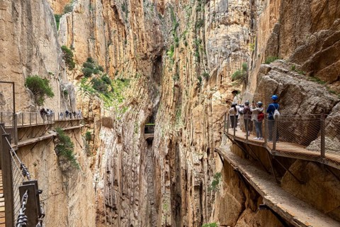 People with helmets walking along the Caminito del Rey in an impressive rocky landscape, Malaga,