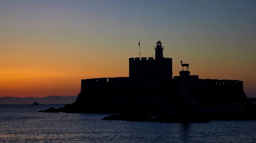 Fortress by the sea silhouetted against a colourful sunrise, dawn, Fort of Saint Nikolaos, Mandraki