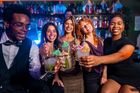 Diverse group of friends raising glasses of mojitos in celebration at a vibrant nightclub, enjoying