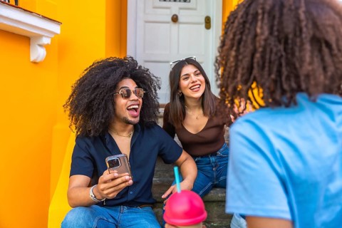 Three cheerful friends enjoying a lively conversation and refreshments while sitting on vibrant