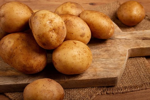 Raw potatoes, scattered on a chopping board, close-up, no people