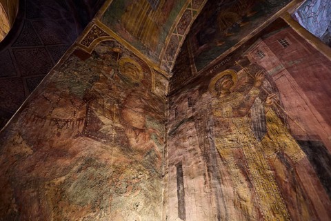 Detailed frescoes in a church depicting saints with halos and architectural elements, Thari