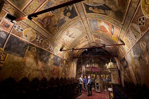 Church interior with detailed wall frescoes and vaulted ceiling, rich religious decorations, Thari