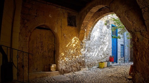 Weathered stone arcade with rays of light falling through an old archway, Rhodes Old Town, Rhodes,