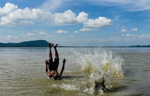 Boys jump in the Brahmaputra river during an a hot summer day in Guwahati, india on July 11, 2022