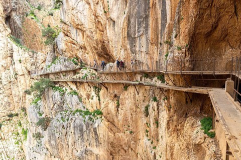 People walking on the narrow Caminito del Rey path that runs along a dramatic cliff face, Malaga,