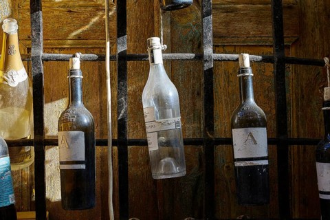 Various bottles hanging from a black metal grid, Symi Town, Symi, Dodecanese, Greek Islands,