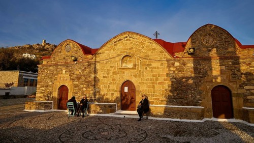 Stone church with rounded roofs and some people walking along in the evening light, Easter 2025,