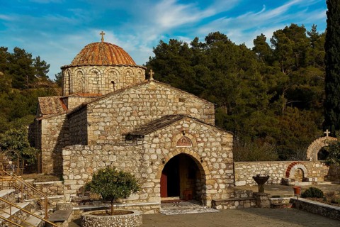 Historic stone church under a blue sky surrounded by trees, Thari Monastery, Moni Thari, near