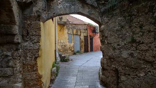 Abandoned corridor with yellow and red walls and stone arches, Rhodes Old Town, Rhodes, Dodecanese,