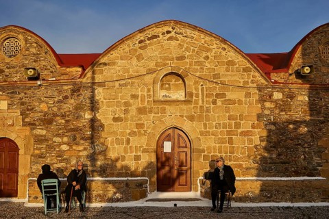 People sitting in front of a stone church in warm light and quiet surroundings, Easter 2025, Church