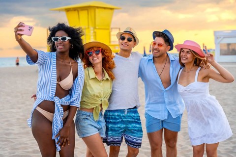 Group of multi ethnic friends taking a selfie on the beach at sunset, enjoying summer holidays