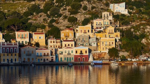 Colourful buildings along the water with some boats on the shore, Mediterranean scenery, Symi town,