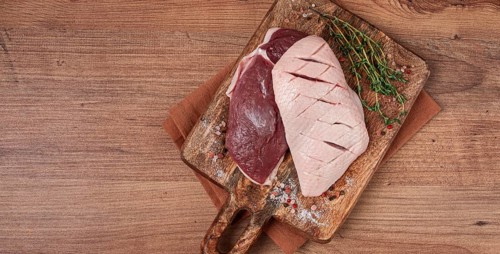 Fresh raw duck breasts, on a wooden chopping board, with herbs and spices, no people