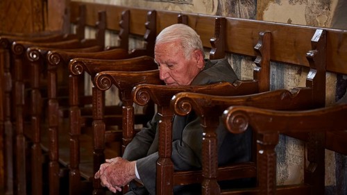 An elderly man leans back in a chair, his eyes closed as if he is sleeping, Easter 2025, Church of