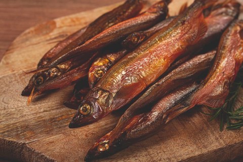 Cold smoked capelin, on a wooden chopping board, no people
