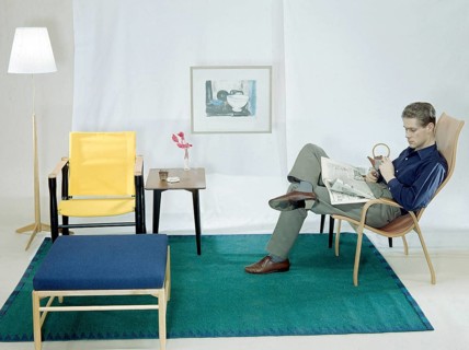 In the 1950s 1960s. A man is sitting comfortably in an armchair reading the newspaper and having a