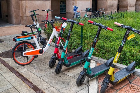 MILAN, ITALY, AUGUST 4, 2021: colorful rental scooters and bicycles on a sidewalk in the city