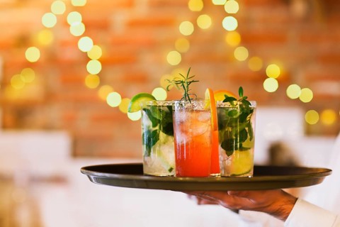 Two cocktail glasses on tray on wooden bar counter