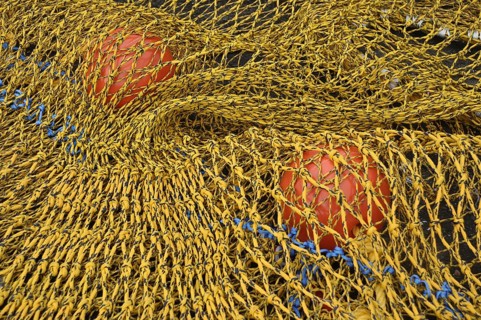 Close-up of a yellow fishing net with red floats and blue rope