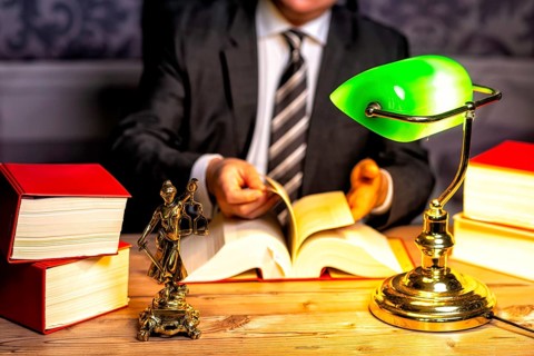 Office of a lawyer with books and a statue of Lady Justice, goddess Justitia, on the desk