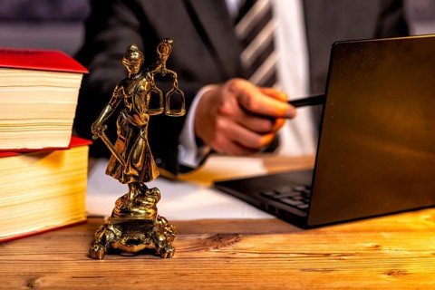 Office of a lawyer with books and a statue of Lady Justice, goddess Justitia, on the desk