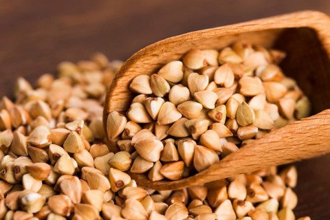 Buckwheat with a spoon on a wooden board background