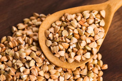 Buckwheat with a spoon on a wooden boards background