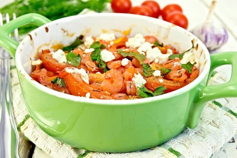 Shrimp and tomatoes baked with feta cheese in a roasting pan on a kitchen towel, parsley and garlic