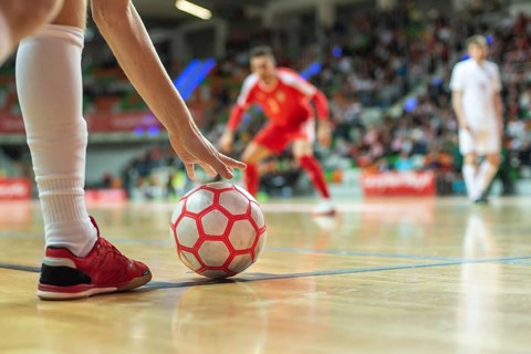 Close up of the futsal ball in the corner and player's leg