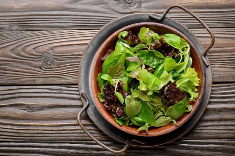Top view at clay dish with green and violet lettuce, lamb's lettuce salad with oregano flowers on