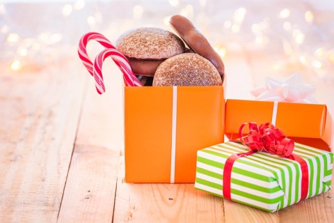 Ton of colorful gifts, one opened full with gingerbread and Xmas candies, laid on a wooden