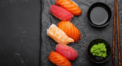 Traditional Japanese sushi with soy sauce, wasabi, chopsticks top view on dark black rustic slate.