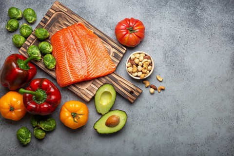 Fresh raw salmon fillet on wooden cutting board, organic bio vegetables and nuts on rustic stone