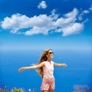 Blond girl shaking hair on air at blue Mediterranean sea tourist in Spain open hands
