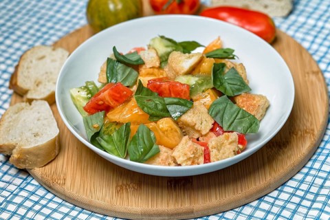 Colourful tomato bread salad with basil in a white bowl