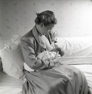 1950s mother nursing her baby. A young woman breastfeeding her baby at home. Sweden 1951 Neg CV/24