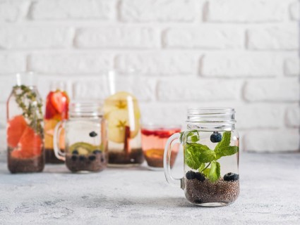 Chia water in mason jar with mint and blueberry on gray cement background. Chia infused detox water