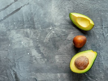 Avocado with copy space. Top view of avocado half, quarter and avocado pit on gray background. Food