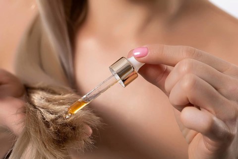 A stylish and fashionable woman carefully applying nourishing hair oil to achieve optimal hydration